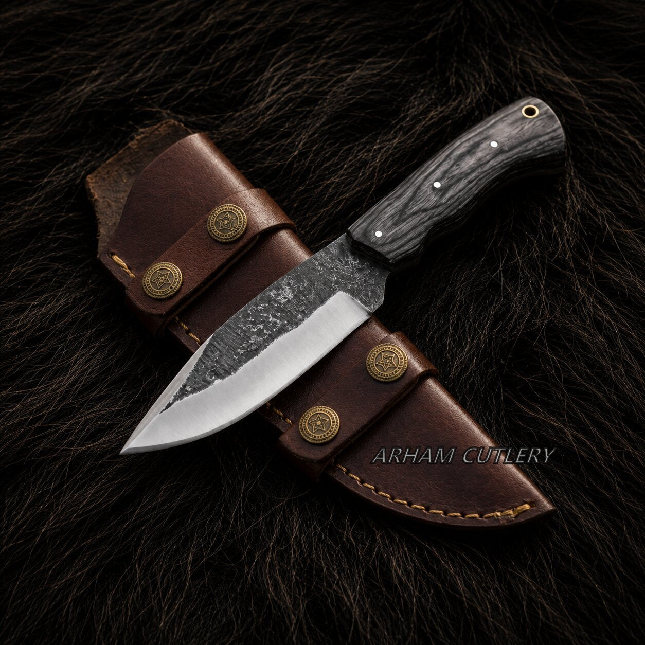 A fixed-blade knife with a dark textured handle and partially serrated steel blade, displayed diagonally on a brown leather sheath over a dark fur background. The brand name 'ARHAM CUTLERY' is visible as a watermark.