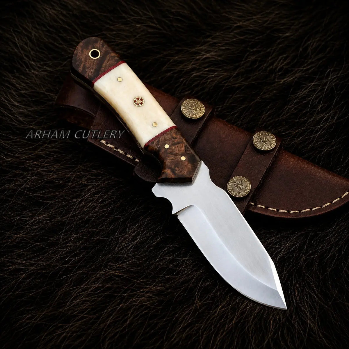 A fixed-blade knife with a polished silver blade, a cream bone handle, and a dark brown wood bolster, displayed diagonally on its brown leather sheath over a dark brown fur background. The brand name 'ARHAM CUTLERY' is watermarked on the left side.