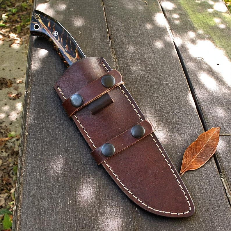 Handmade D2 steel hunting knife with black and amber resin handle on wooden surface – Arham Cutlery