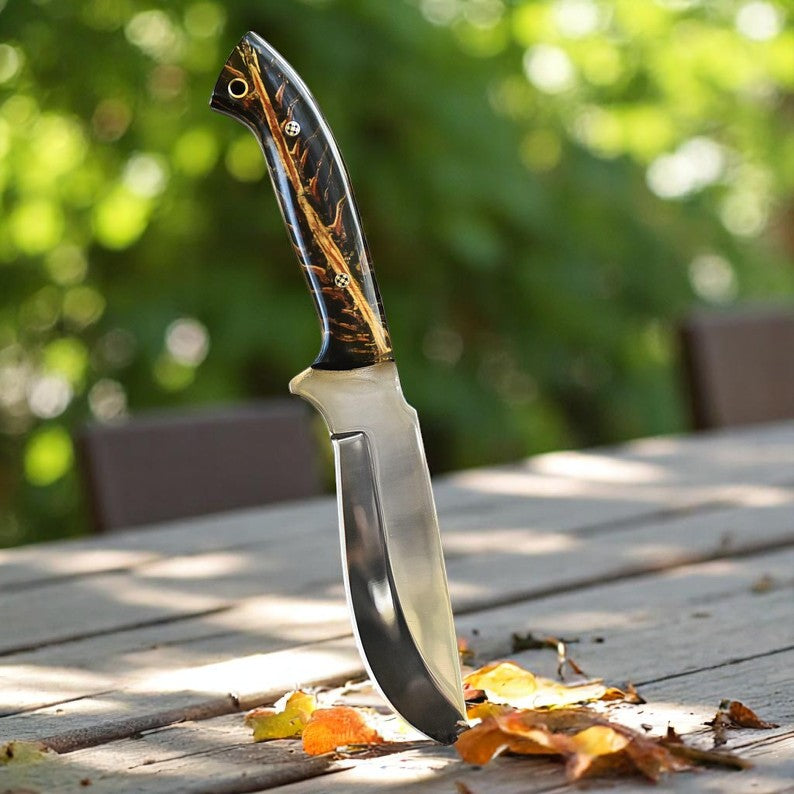 Handmade D2 steel hunting knife with black and amber resin handle on wooden surface – Arham Cutlery