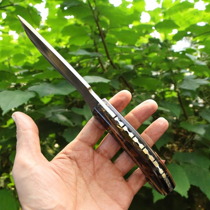 Handmade D2 steel hunting knife with black and amber resin handle on wooden surface – Arham Cutlery