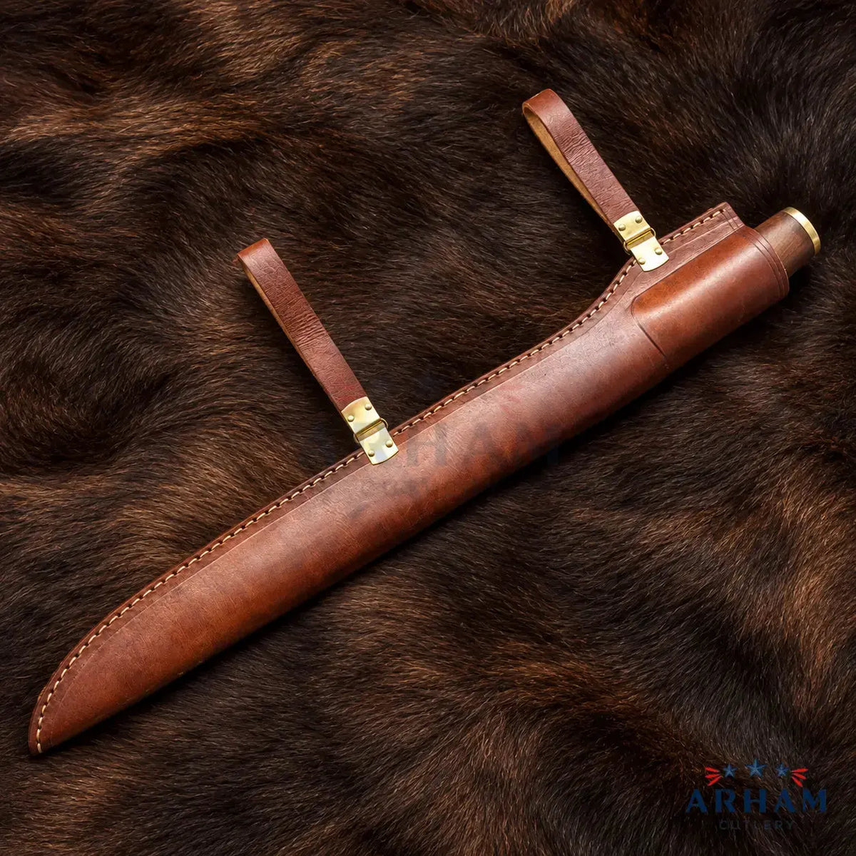 A brown leather sheath with brass hardware, laid diagonally on a dark brown fur background. The sheath has two leather loops with brass clasps and a brass tip at one end.
