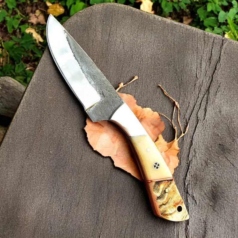 Custom fixed-blade knife with D2 steel and natural ram horn/camel bone handle displayed on a table.