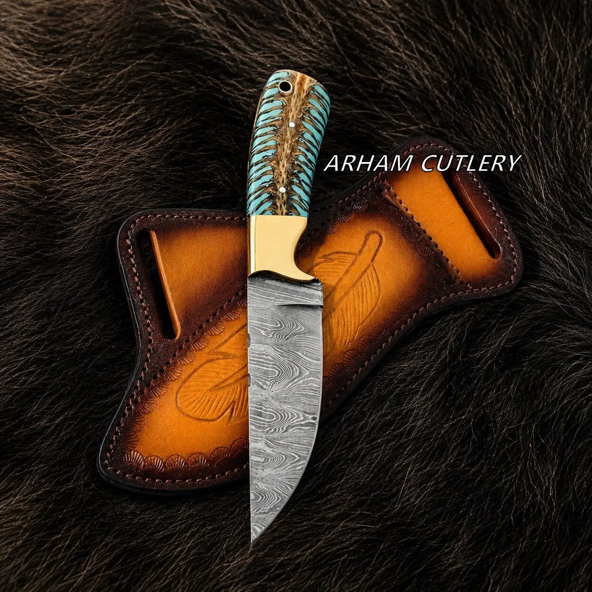 A fixed-blade knife with a patterned steel blade, turquoise and brown wrapped handle, and brass bolster, displayed upright in front of a brown leather sheath on a dark fur background. The text 'ARHAM CUTLERY' appears on the right.