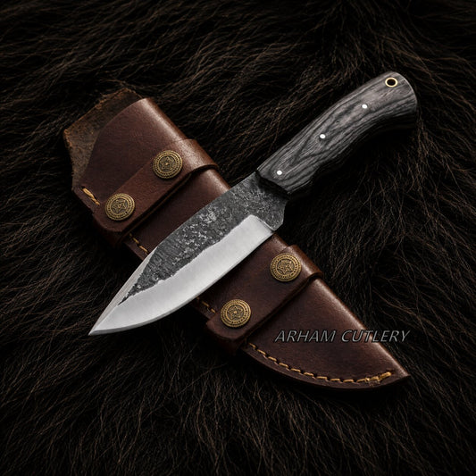 A fixed-blade knife with a dark textured handle and partially serrated steel blade, displayed diagonally on a brown leather sheath over a dark fur background. The brand name 'ARHAM CUTLERY' is visible as a watermark.