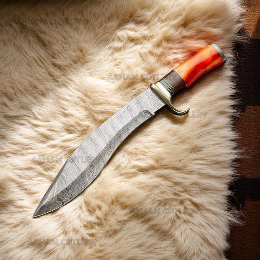 Handmade Damascus Bowie knife with orange camel bone, rosewood handle, and brass guard on sheepskin surface – Arham Cutlery