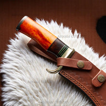 Lade das Bild in den Galerie-Viewer, Handmade Damascus Bowie knife with orange camel bone, rosewood handle, and brass guard on sheepskin surface – Arham Cutlery
