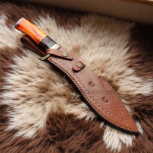 Lade das Bild in den Galerie-Viewer, Handmade Damascus Bowie knife with orange camel bone, rosewood handle, and brass guard on sheepskin surface – Arham Cutlery
