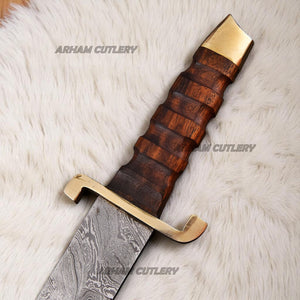 Hand-forged Damascus steel short sword with wooden handle and brass accents by Arham Cutlery, displayed on a wooden surface