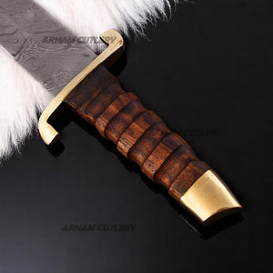 Hand-forged Damascus steel short sword with wooden handle and brass accents by Arham Cutlery, displayed on a wooden surface