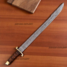 Cargar imagen en el visor de la galería, Hand-forged Damascus steel short sword with wooden handle and brass accents by Arham Cutlery, displayed on a wooden surface
