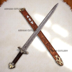 Hand-forged Viking Damascus steel sword with engraved wooden scabbard and ornate brass fittings displayed on a dark wooden background