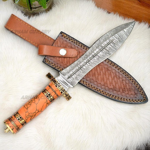 Damascus Steel Bowie Knife with Orange Turquoise and Brass Handle and Leather Sheath on White Fur Background