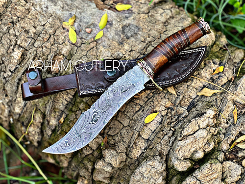 Steelroot – 13-Inch Damascus Steel Hunting Knife with Rosewood and Brass Handle, displayed on bark with handmade leather sheath – Arham Cutlery