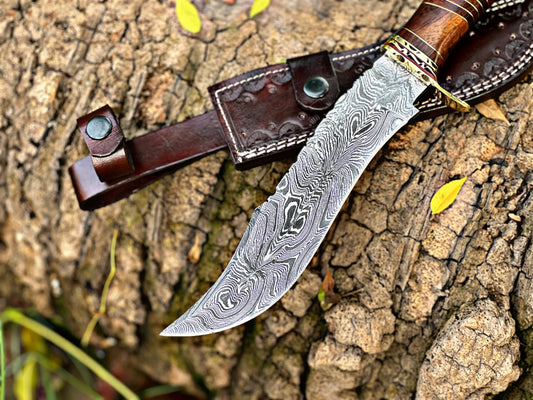 Steelroot – 13-Inch Damascus Steel Hunting Knife with Rosewood and Brass Handle, displayed on bark with handmade leather sheath – Arham Cutlery