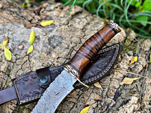 Cargar imagen en el visor de la galería, Steelroot – 13-Inch Damascus Steel Hunting Knife with Rosewood and Brass Handle, displayed on bark with handmade leather sheath – Arham Cutlery
