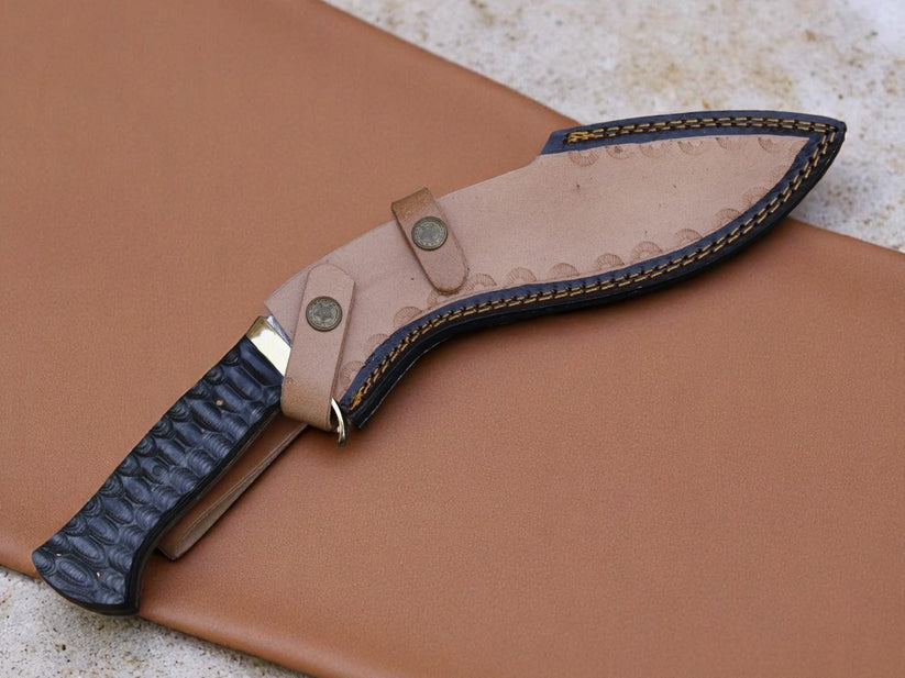 A fixed-blade knife with a textured black handle and a tan leather sheath, displayed diagonally on a matching tan leather background.