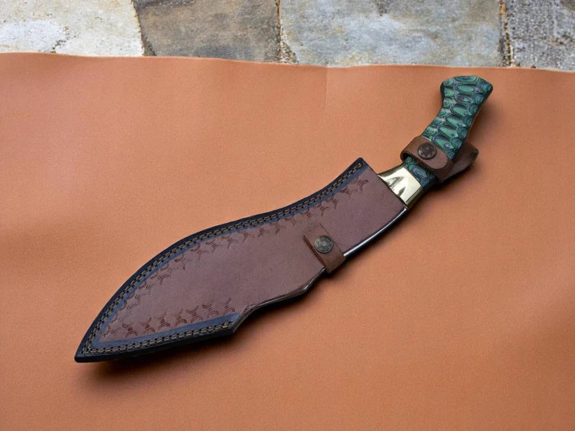 A fixed-blade knife with a textured green handle and a brown leather sheath, displayed diagonally on a sheet of brown leather with a stone floor in the background.