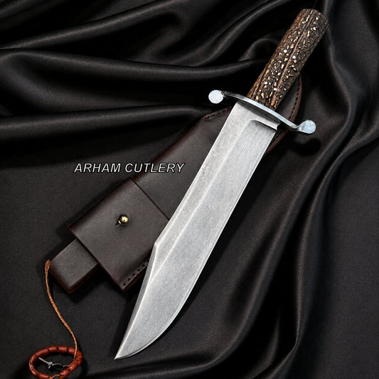 A fixed-blade knife with a silver steel blade, a textured brown handle, and a dark brown leather sheath, arranged on draped black satin fabric. The brand name 'ARHAM CUTLERY' is printed in white text across the center.