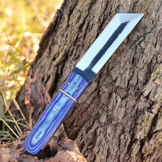 A fixed-blade knife with a polished silver blade and a blue marbled handle, resting diagonally on a textured tree trunk outdoors.