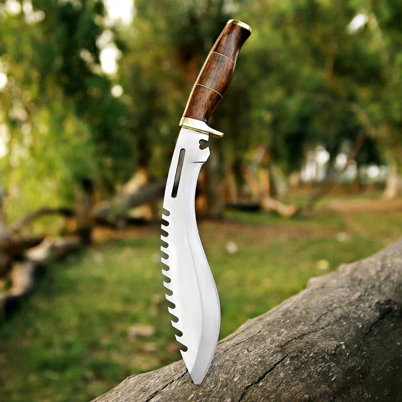 A curved fixed-blade knife with a silver serrated blade and a brown wooden handle, shown standing upright on a log with a blurred outdoor forest background.