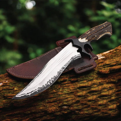 A fixed-blade knife with a patterned silver blade, black guard, and brown handle, resting on a brown leather sheath atop a log with a blurred forest background.
