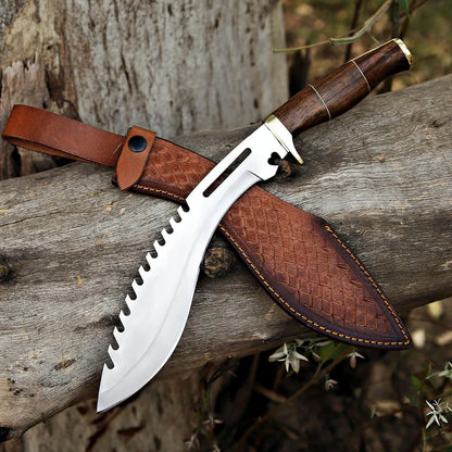 A fixed-blade machete-style knife with a serrated silver blade, dark brown wooden handle, and matching brown leather sheath, resting on a weathered log outdoors.