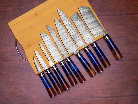 A set of eight kitchen knives with patterned steel blades and dark blue to brown wooden handles, displayed on a light wood cutting board over a dark wood surface.