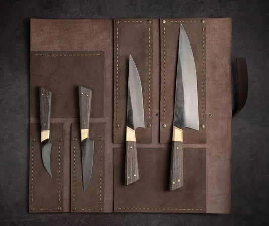 A set of four kitchen knives with dark wood handles and silver blades, displayed inside an open brown leather roll-up case on a dark textured background.