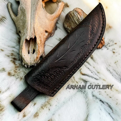 A dark brown leather knife sheath with embossed leaf detailing, shown on a white fur surface with a deer skull and wood prop. The text 'ARHAM CUTLERY' is overlaid on the image.