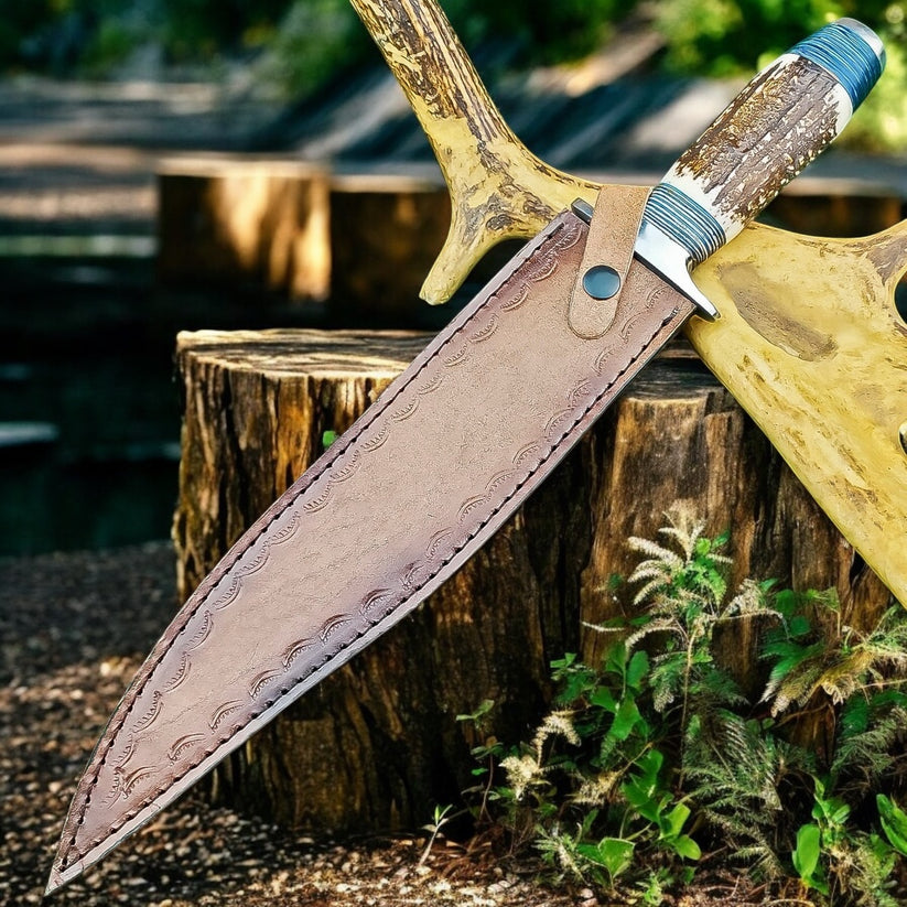 A large fixed-blade knife with a brown leather sheath, resting on a rustic wooden stump in an outdoor setting with trees and plants in the background.