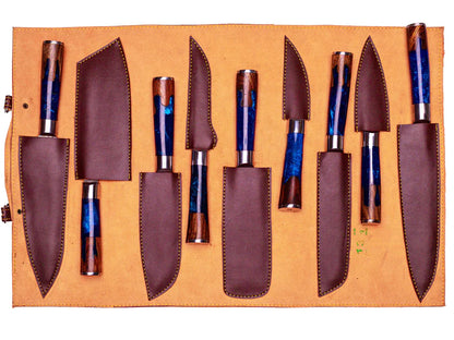 A set of kitchen knives with blue and brown marbled resin handles, displayed in a tan leather roll-up case with matching brown sheaths.