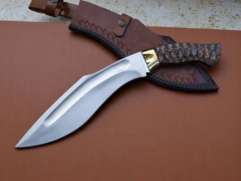 A fixed-blade knife with a polished silver blade, gold-toned bolster, and a carved dark wood handle, displayed next to its brown leather sheath on a brown leather surface.