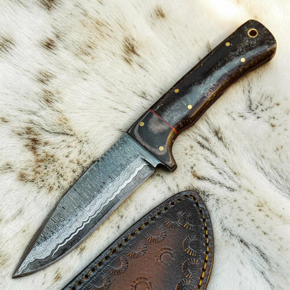 A fixed-blade knife with a patterned steel blade and a dark brown wooden handle with brass pins, shown alongside a brown leather sheath on a white and brown animal fur background.