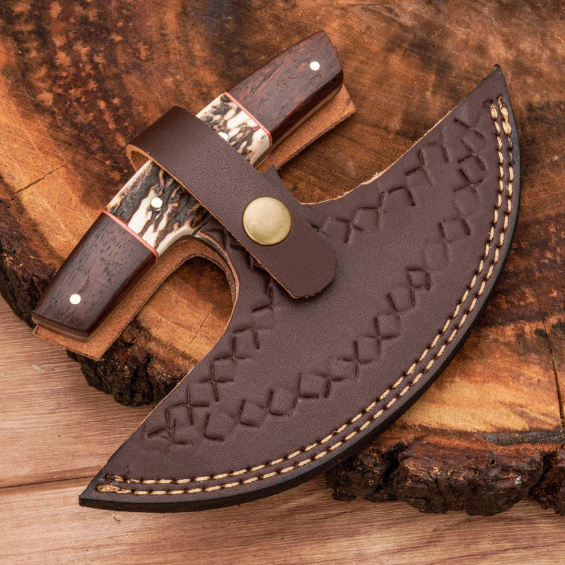 A curved brown leather knife sheath with embossed geometric stitching and contrast stitching, shown with a partially unsheathed knife featuring dark wood handles and bone inlays, placed on a rustic wood log background.