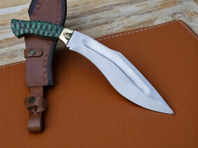 A curved fixed-blade knife with a polished silver blade and a textured green handle, shown alongside a brown leather sheath on a brown leather surface.