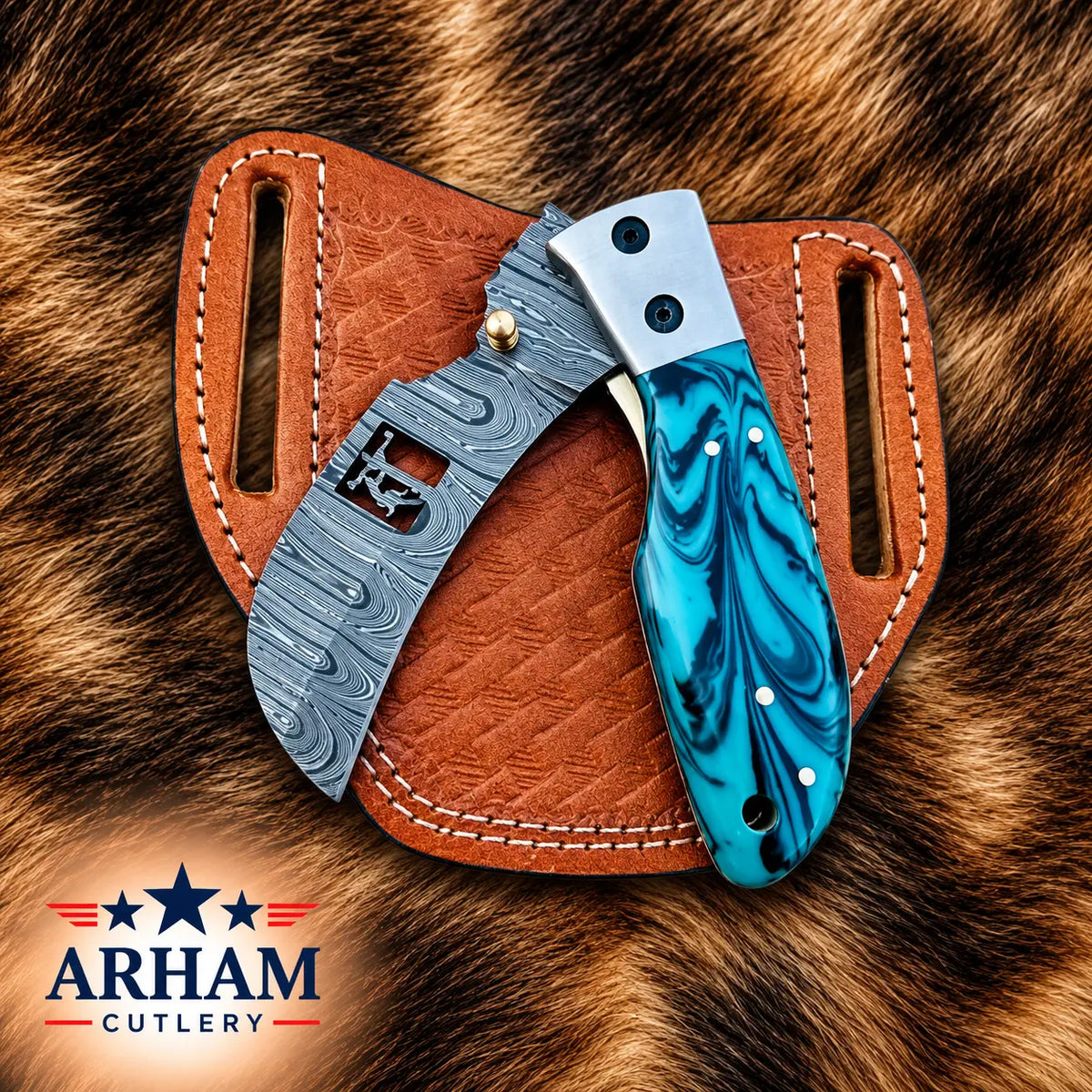 A folding knife with a blue marbled handle and a patterned steel blade, displayed in a brown leather sheath on a brown fur background. The Arham Cutlery logo is visible in the bottom-left corner.