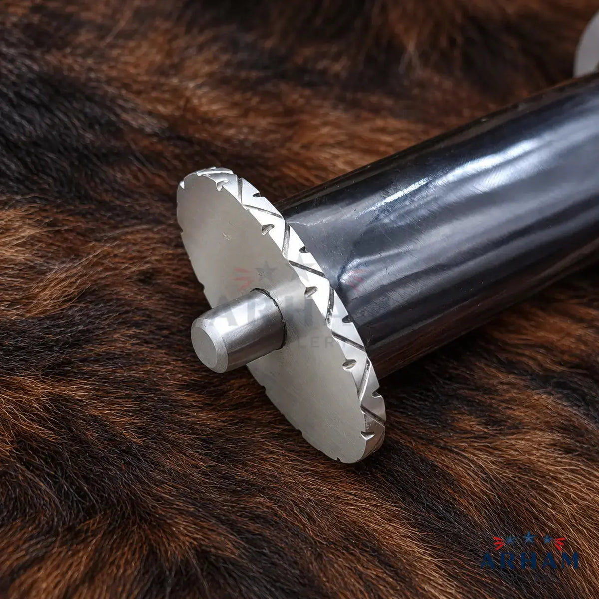 A close-up of a metal cylindrical tool or shaft with a circular saw-like end, resting on a brown fur surface.