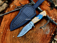 Cargar imagen en el visor de la galería, Hand-forged Damascus steel knife with epoxy and wood handle and custom leather sheath by Arham Cutlery, displayed on a wooden surface.
