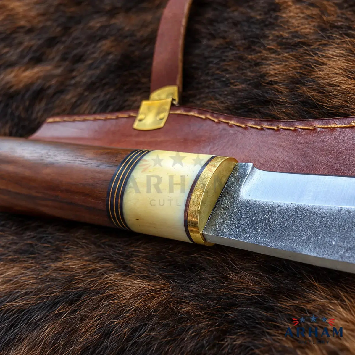 A close-up of a fixed-blade knife with a polished dark wood handle, a silver steel blade, and brass and ivory-colored guard details, resting on a brown leather sheath over a dark brown fur background.
