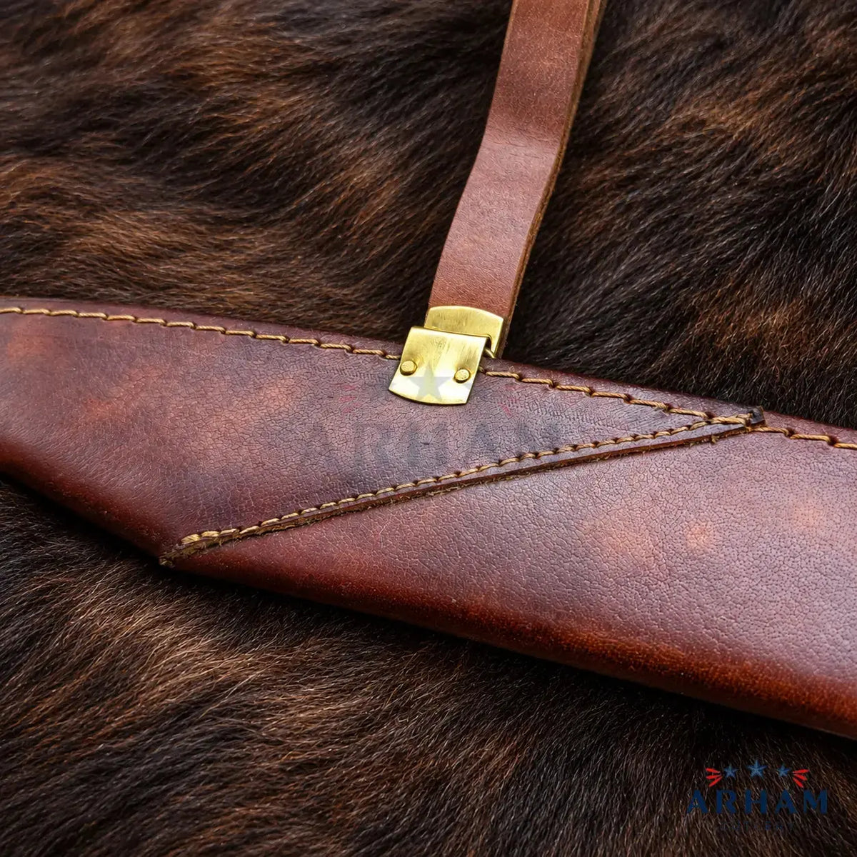 A close-up of a brown leather sheath with a brass buckle, laid on a dark brown fur surface. A faint ARRIA watermark is visible across the center, and an ARRIA logo appears in the bottom right corner.