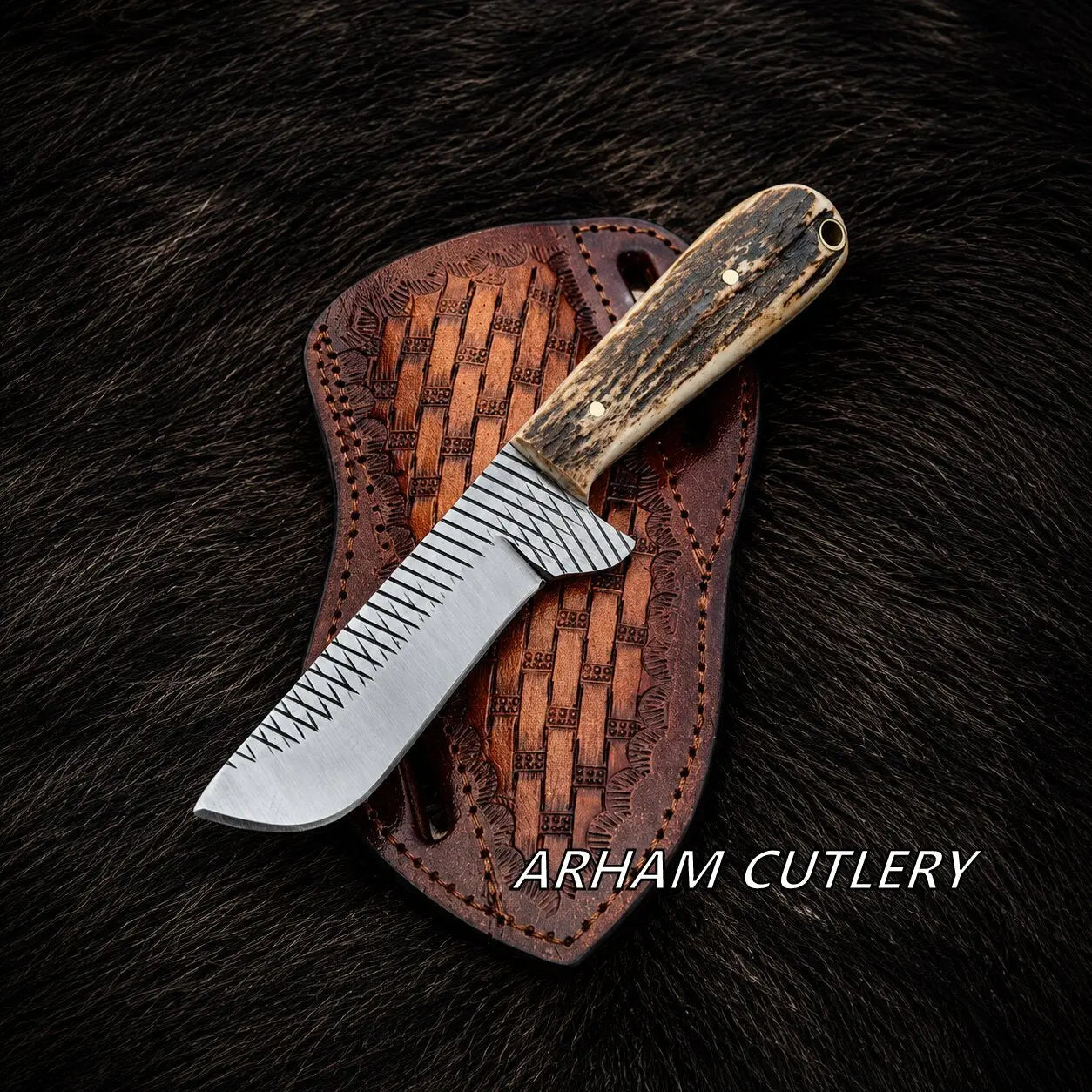 A fixed-blade knife with a patterned silver blade and a dark wood handle rests on a brown woven leather sheath over a dark fur background. The text 'ARHAM CUTLERY' is visible at the bottom right.