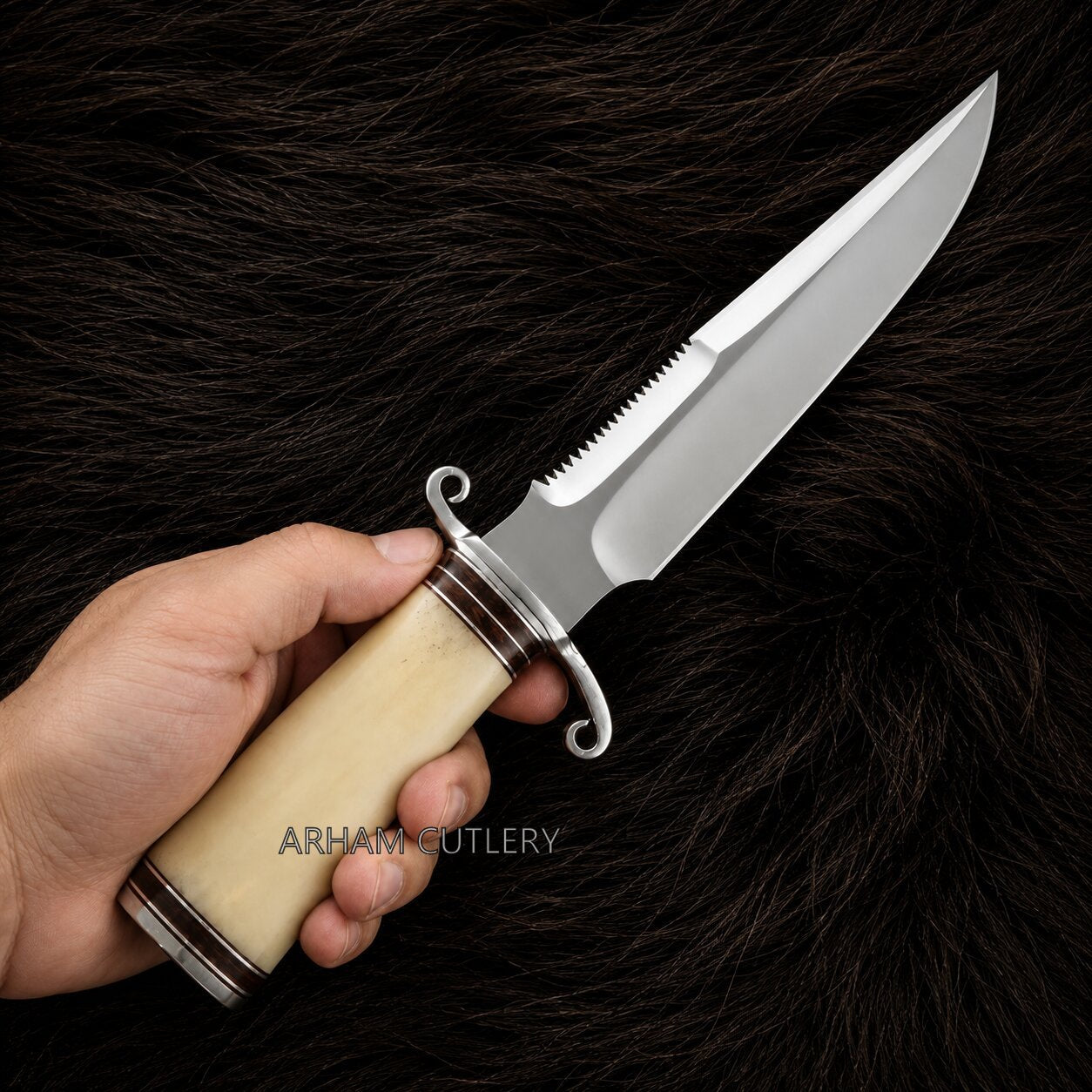 A hand holding a fixed-blade knife with a polished silver blade, a cream-colored bone handle, and silver guard details, set against a dark brown fur background. The text 'ARHAR CUTLERY' is visible on the handle.