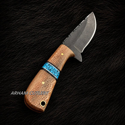 A custom fixed-blade knife with a textured brown wood handle, a turquoise inlay, and a dark steel blade, displayed diagonally on a black textured fur background. The brand name 'ARHAM CUTLERY' is visible as a watermark on the lower left of the handle.