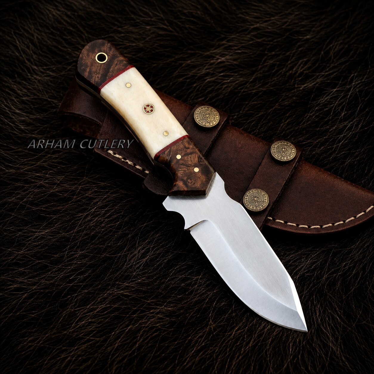 A fixed-blade knife with a polished silver blade, a cream bone handle, and a dark brown wood bolster, displayed diagonally on its brown leather sheath over a dark brown fur background. The brand name 'ARHAM CUTLERY' is watermarked on the left side.