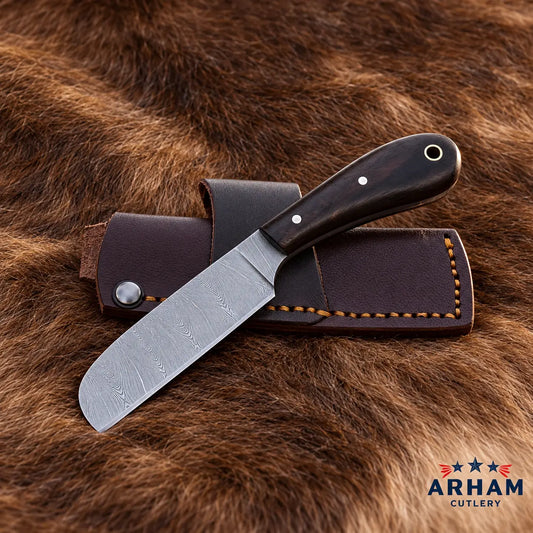 A fixed-blade knife with a patterned steel blade and dark wood handle rests on a dark brown leather sheath over a brown fur background. The ARHAM CUTLERY logo is visible in the bottom right corner.