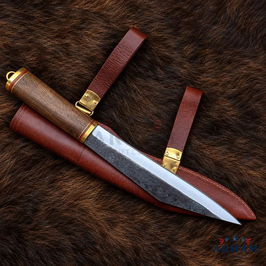 A fixed-blade knife with a patterned steel blade, a dark wood handle, and brass accents, shown alongside a brown leather sheath on a brown fur background.