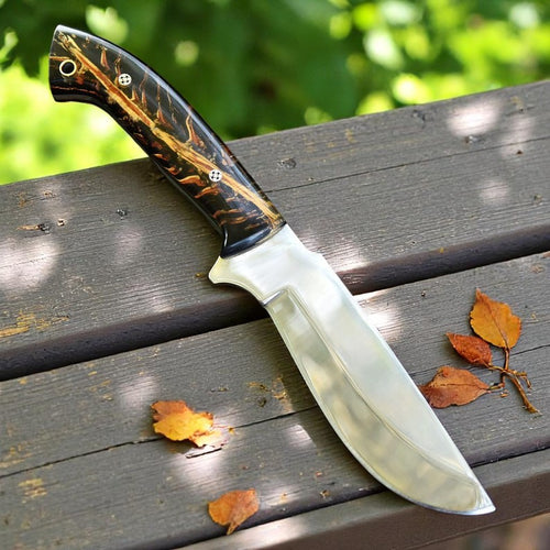 Handmade D2 steel hunting knife with black and amber resin handle on wooden surface – Arham Cutlery