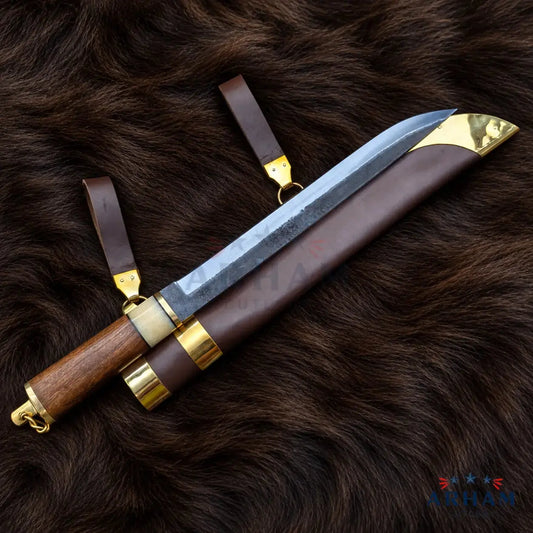 A fixed-blade knife with a textured steel blade, a brown wooden handle, and a brown leather sheath, displayed on a dark brown fur background. The sheath features brass/gold-colored metal accents and a matching leather loop with a brass ring.