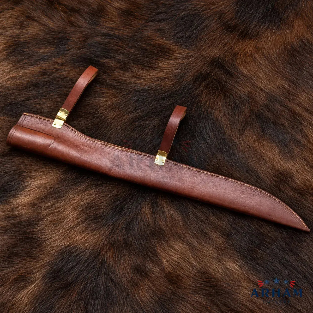 A brown leather knife sheath with brass-colored metal accents, laid diagonally on a dark brown animal fur background.